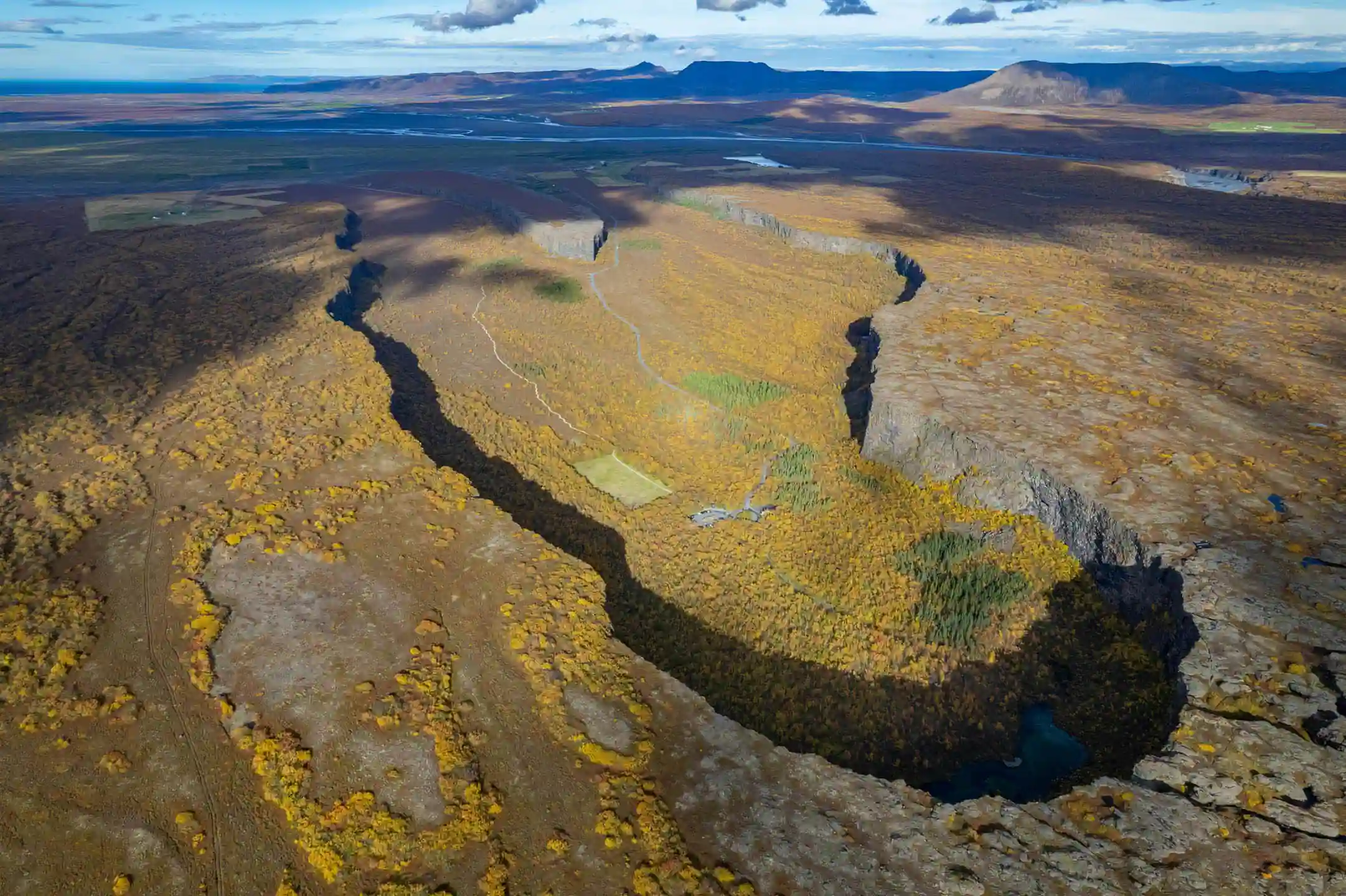 North Iceland road trip stop at Ásbyrgi Canyon with aerial view of horseshoe-shaped cliffs and birch forest