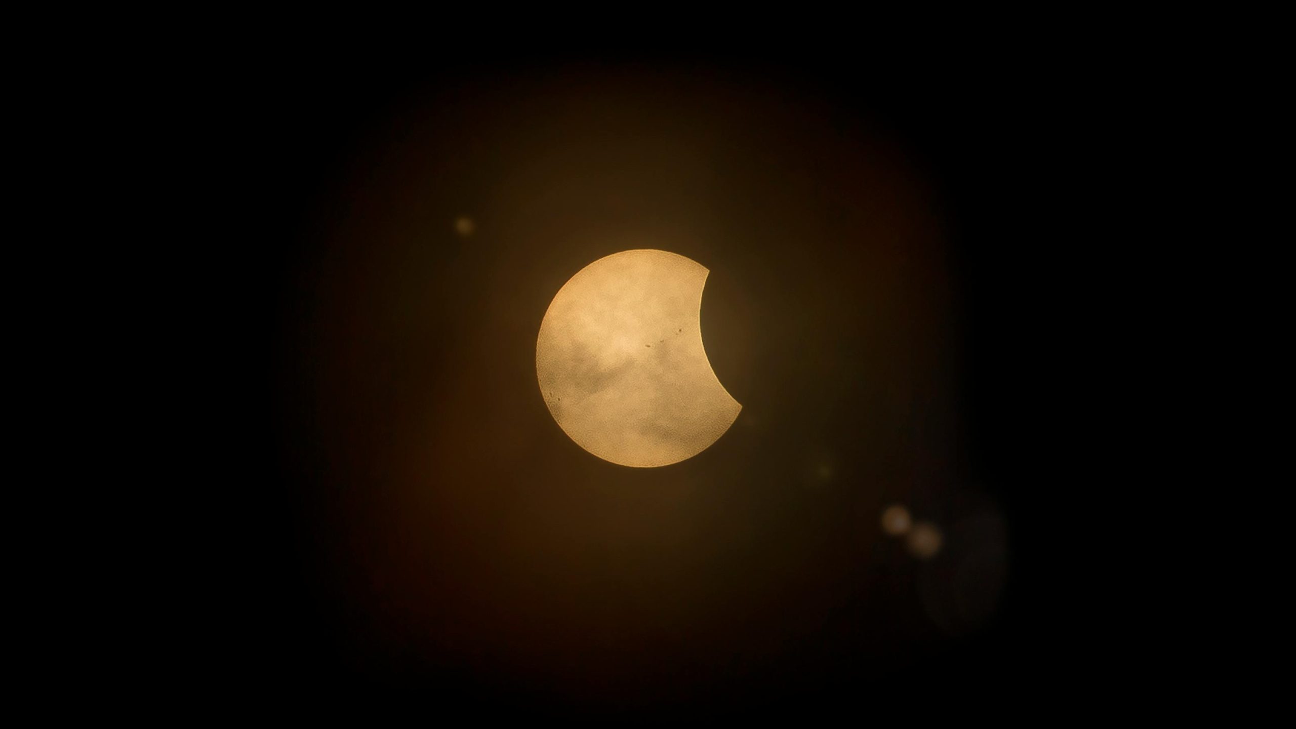 Partial solar eclipse with crescent-shaped sun and golden glow surrounded by black night sky