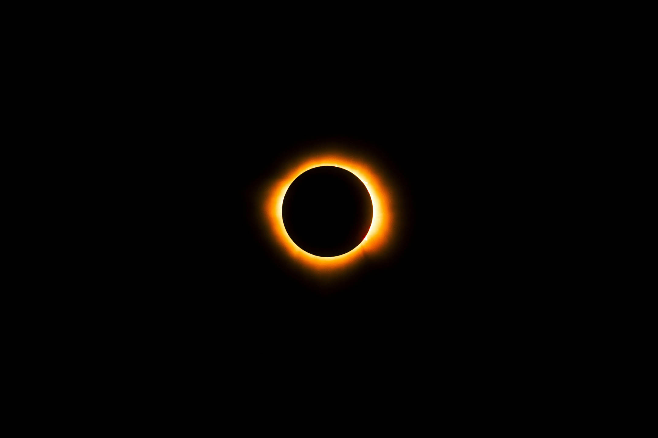 Total solar eclipse with bright corona ring and blackened sun disc against dark sky