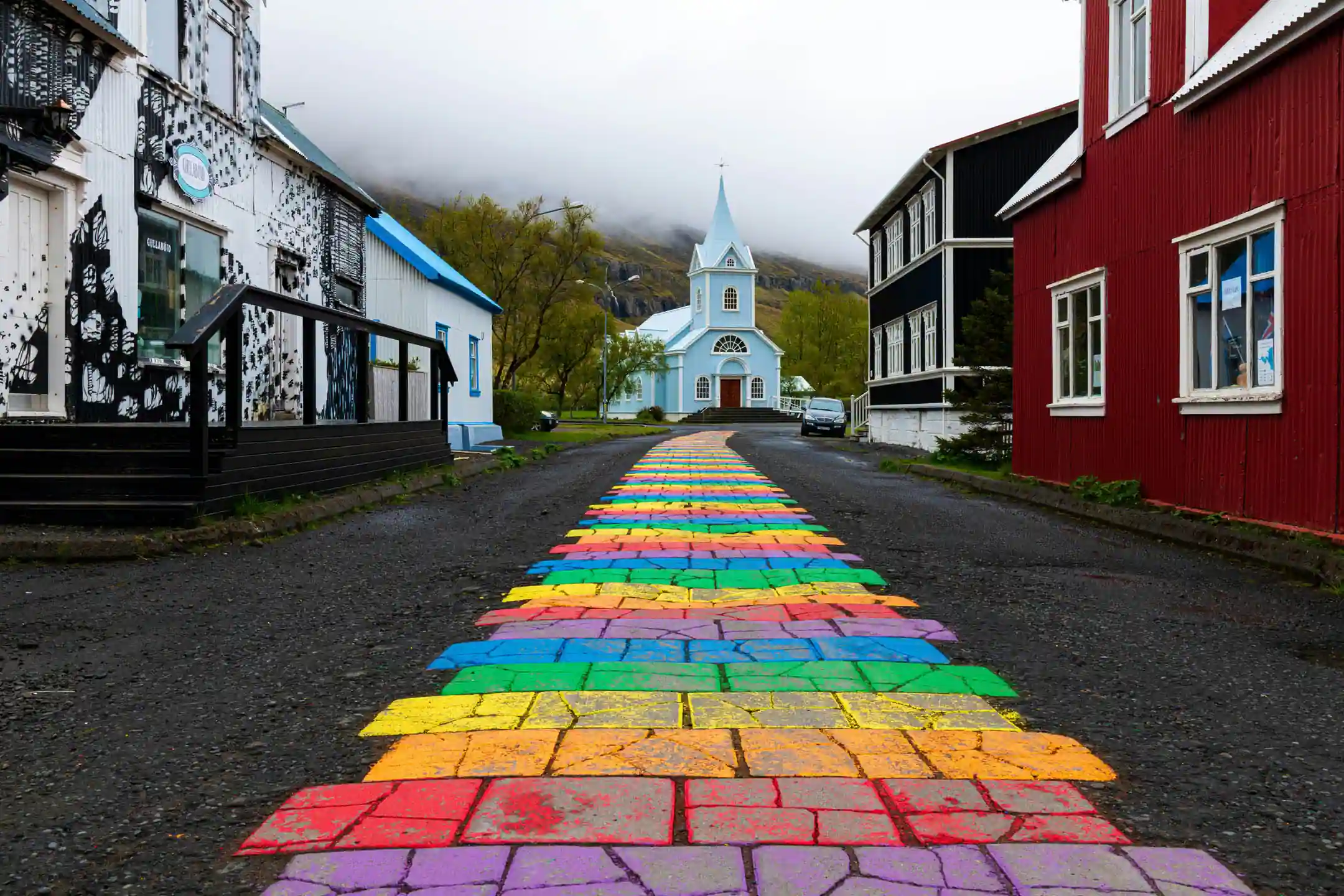 Colorful Rainbow Street leading to the blue church in Seyðisfjörður village in East Iceland