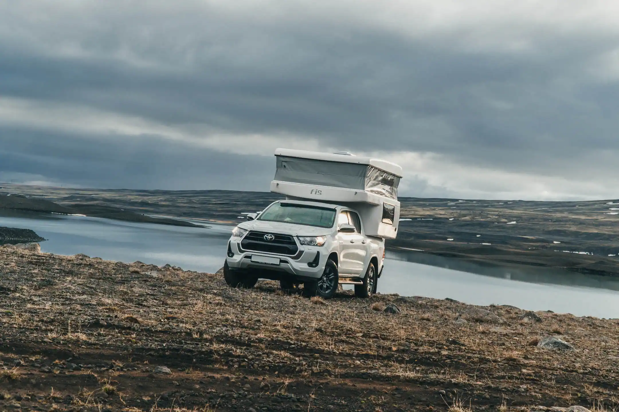 4x4 campervan in Iceland parked by a remote volcanic lake landscape