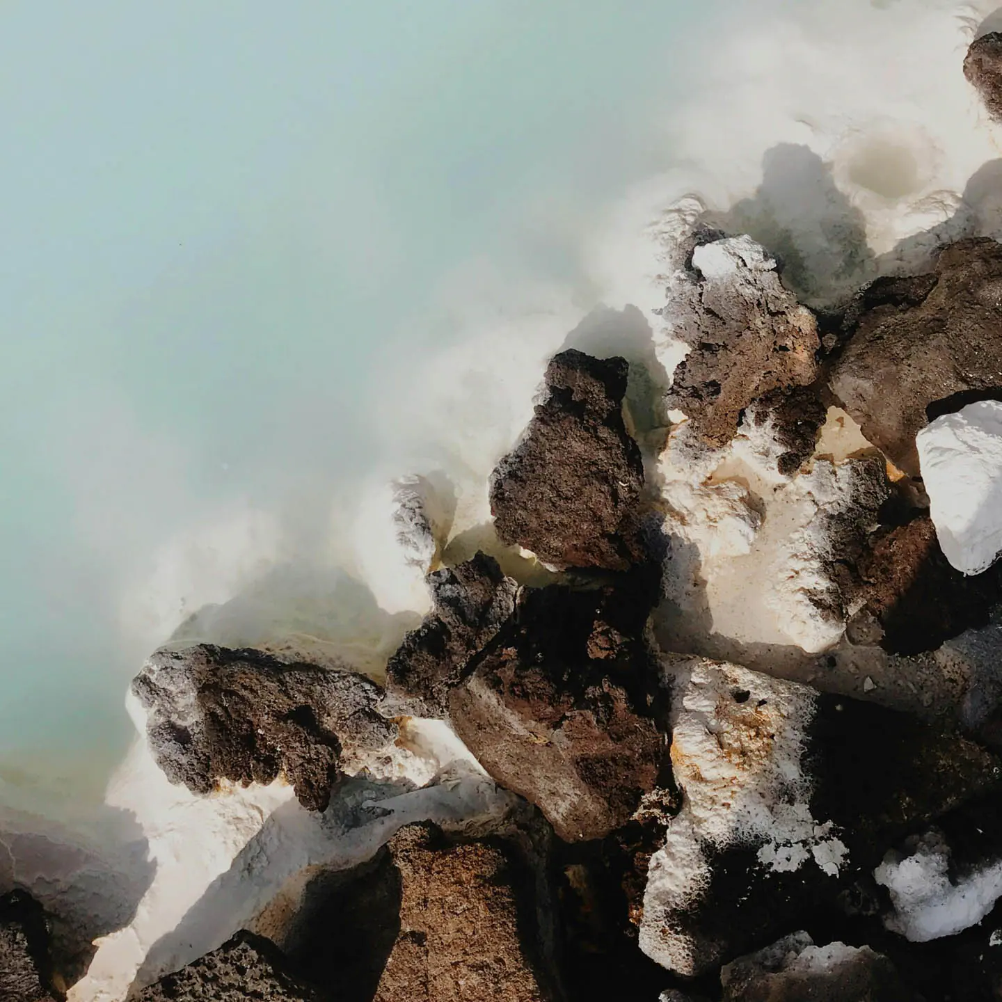 Close-up of geothermal water and lava rocks at a natural hot spring in Iceland.