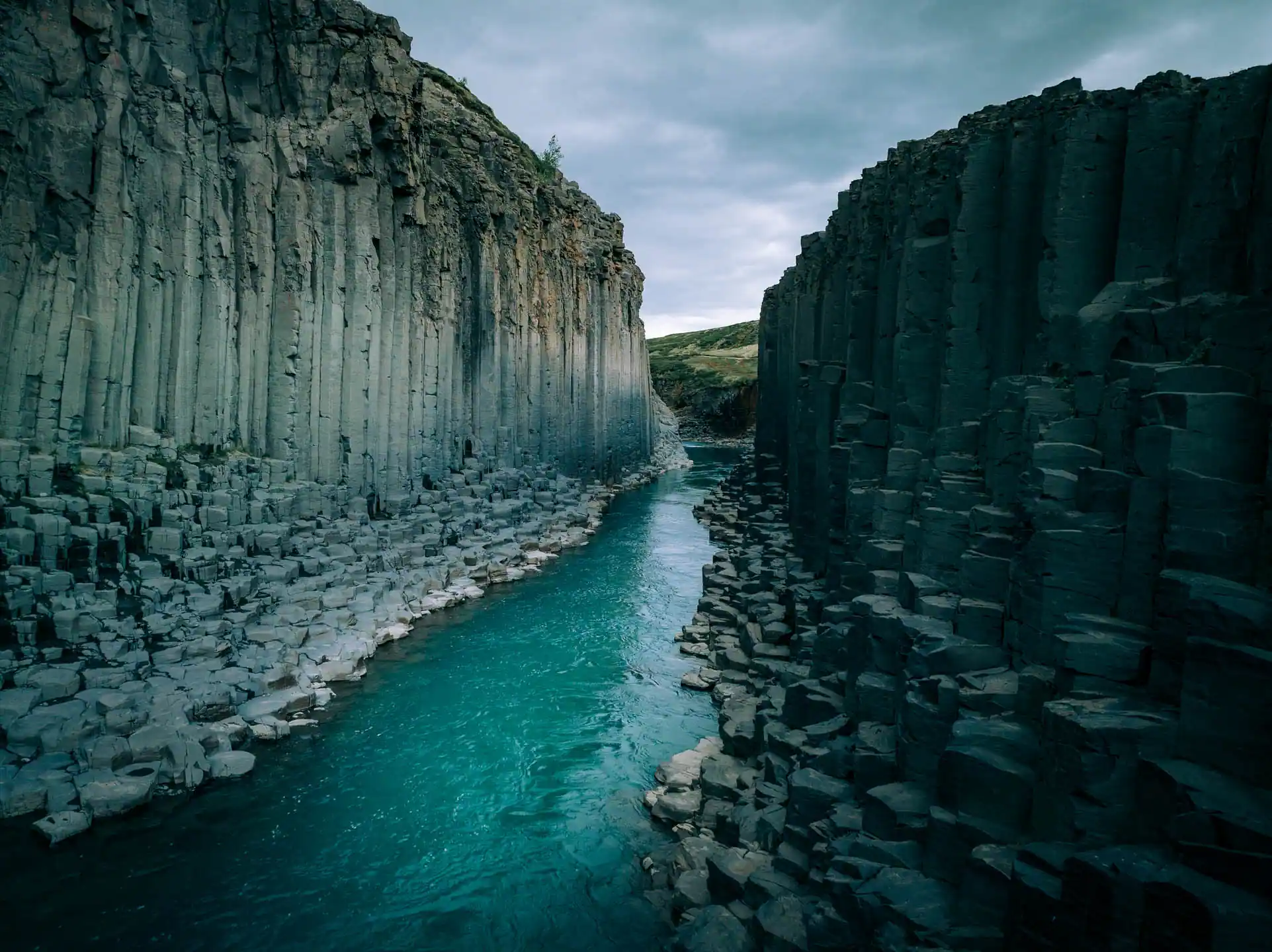 Basalt column walls rising above the turquoise river in Stuðlagil Canyon in East Iceland