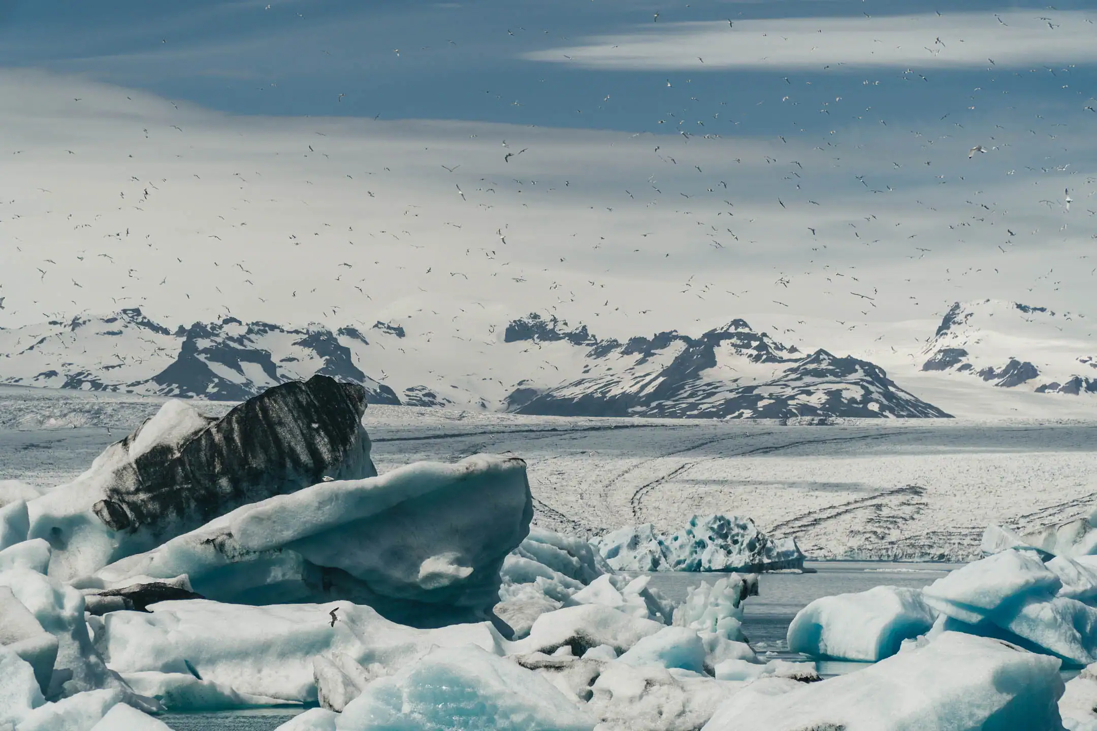 Floating blue icebergs at Jökulsárlón glacier lagoon with snow-capped mountains in Vatnajökull National Park, Iceland