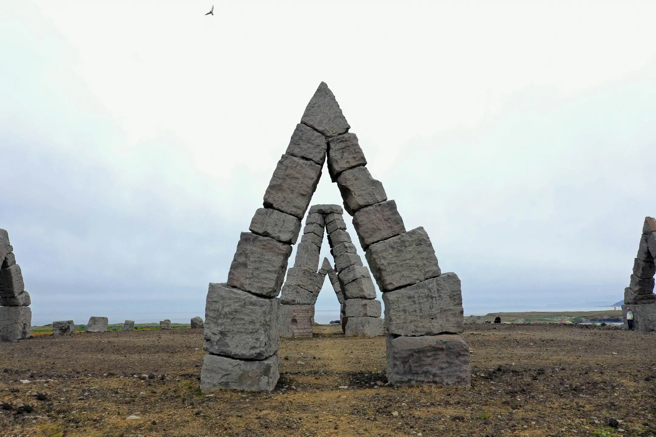 “Arctic Henge stone arch in North Iceland shown on a cloudy day, with triangular basalt blocks forming geometric gates across a barren volcanic landscape.” 