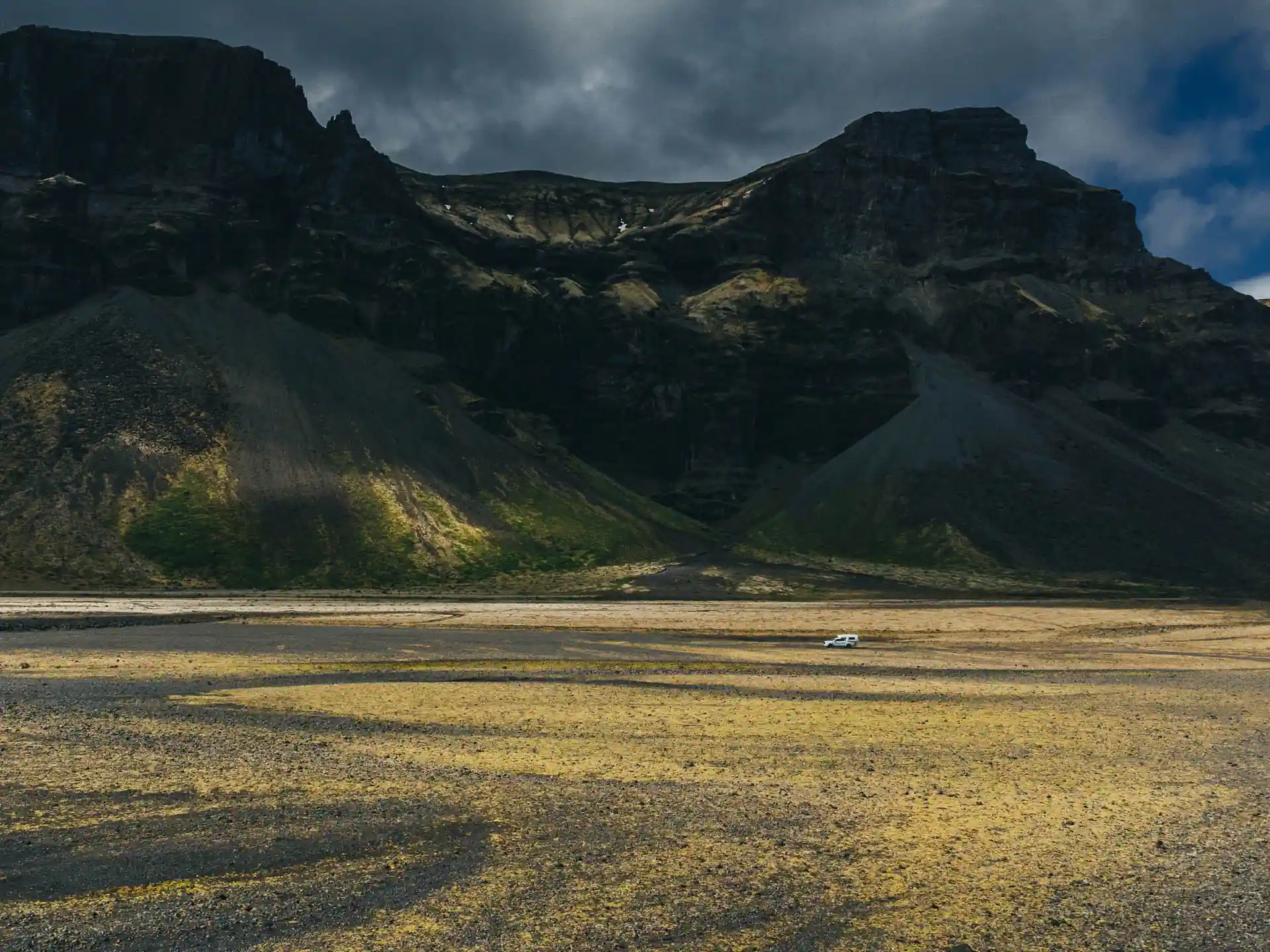Campervan safely parked beneath volcanic mountains in Iceland.