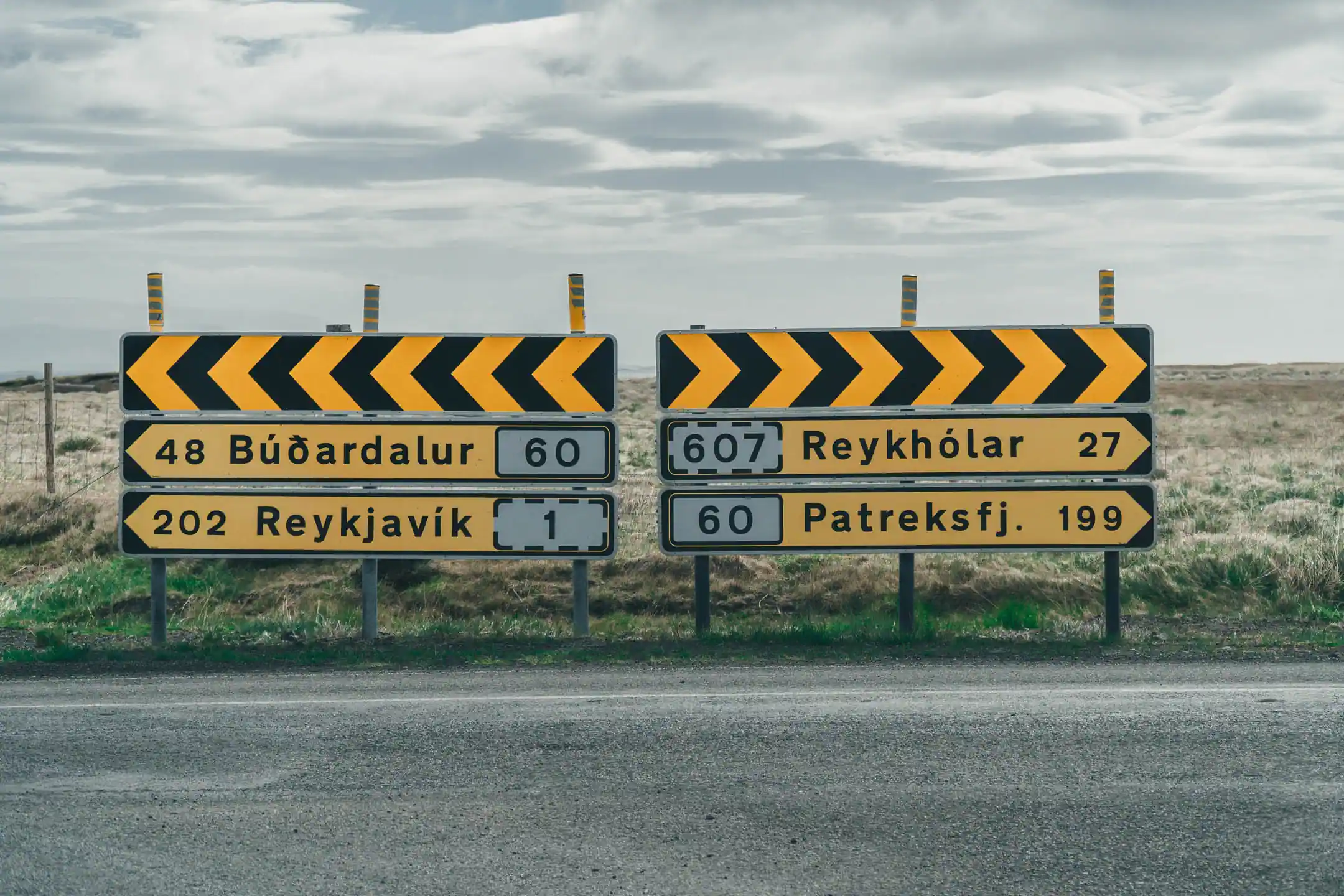 Directional road signs in rural Iceland showing distances to Reykjavík, Reykhólar, Búðardalur, and Patreksfjörður during a campervan road trip