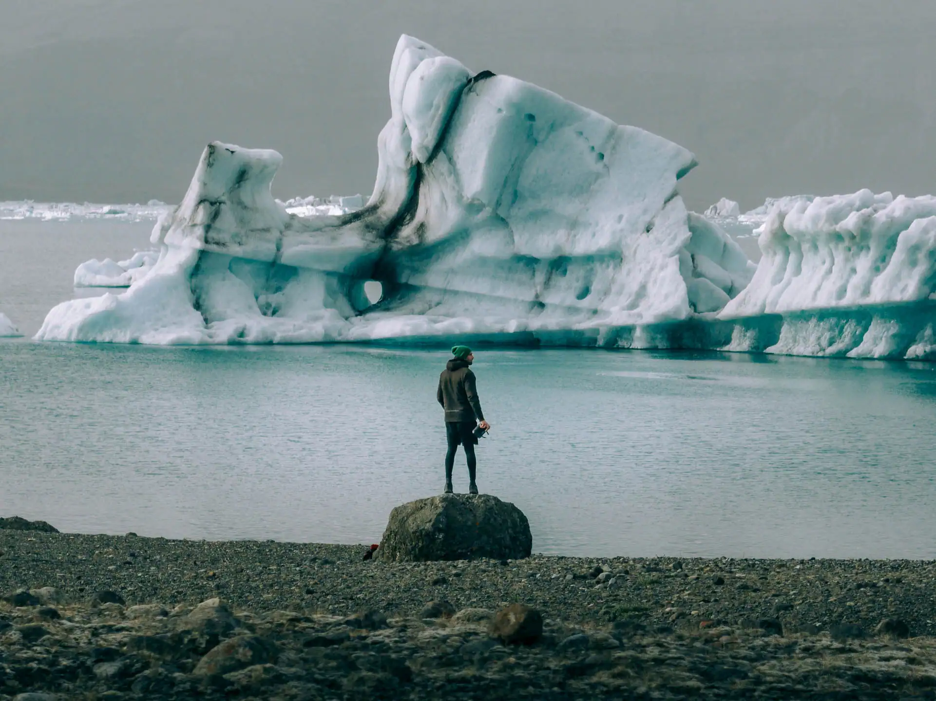 Traveler standing near floating icebergs at a glacier lagoon in Iceland during a campervan road trip adventure