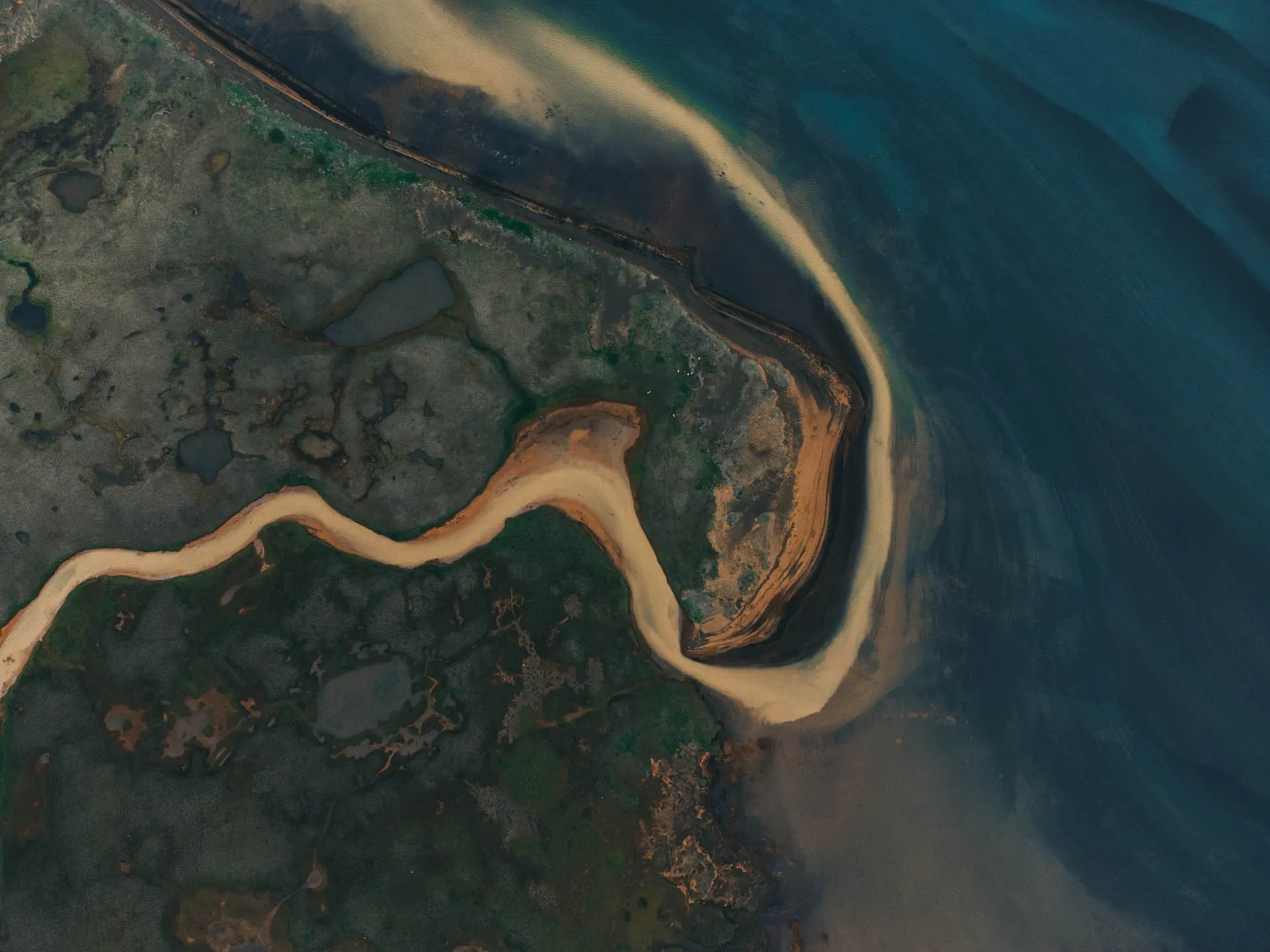 Aerial view of a river flowing into the ocean along Iceland’s rugged coastline 