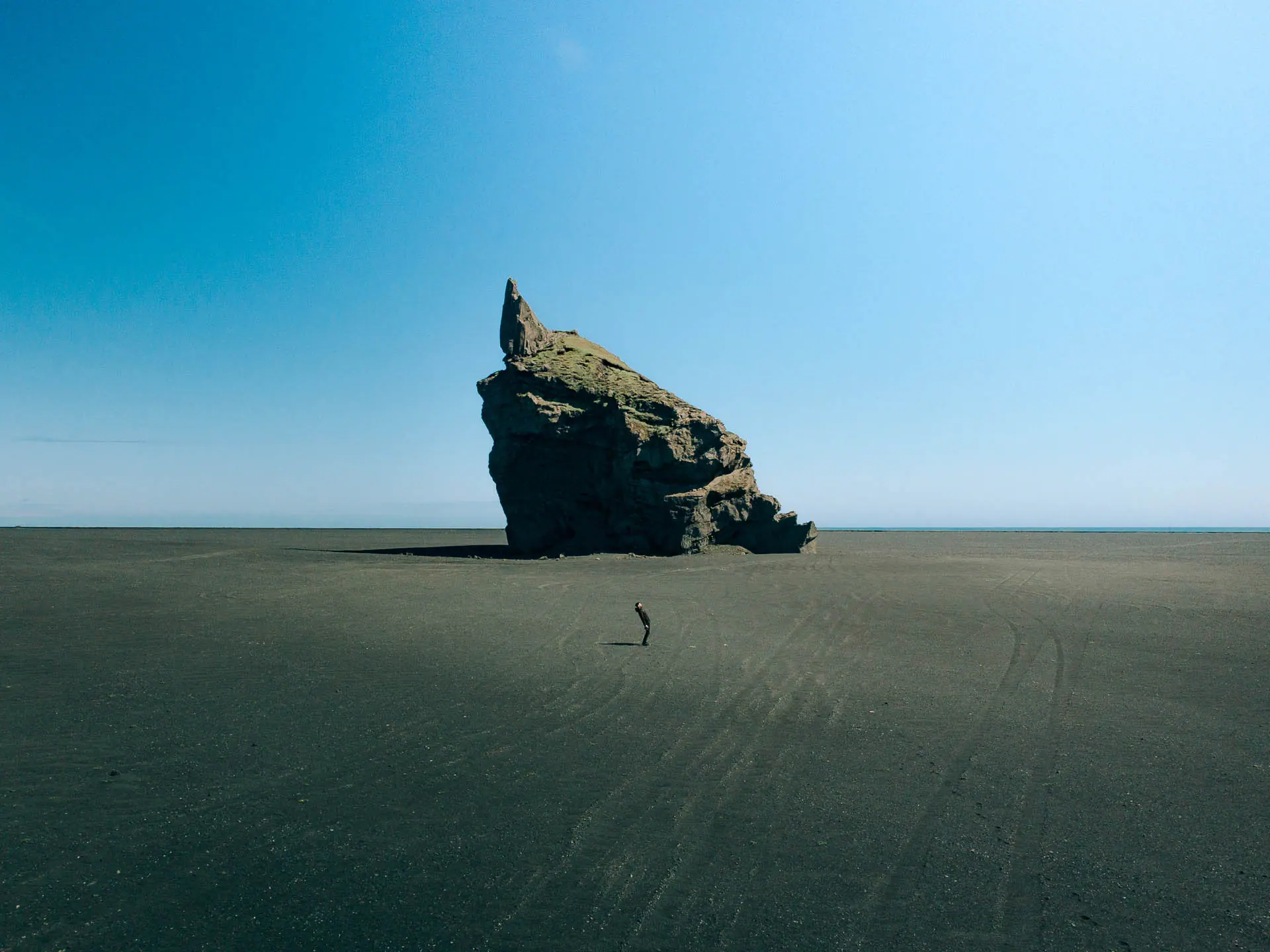 traveler walking on black sand near the Hvitserkur sea stack along the Ring Road in Iceland during a campervan road trip