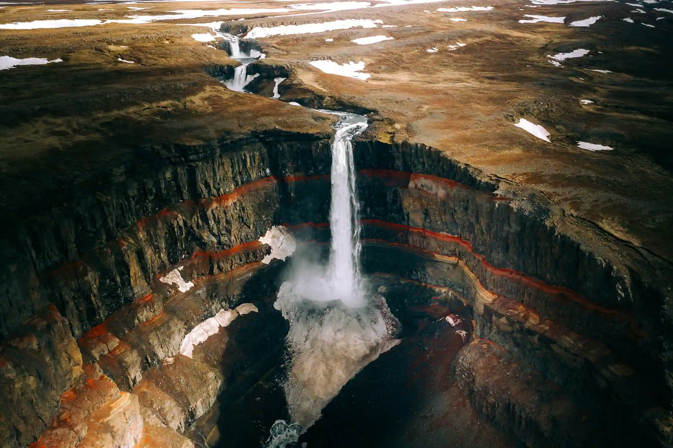 Háifoss waterfall in Iceland dropping into a deep canyon with colorful volcanic rock layers and highland landscape