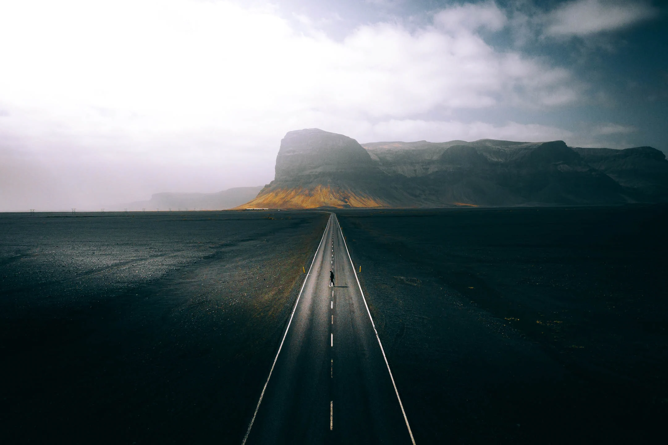 Iceland landscape and person standing in the middle of an empty road